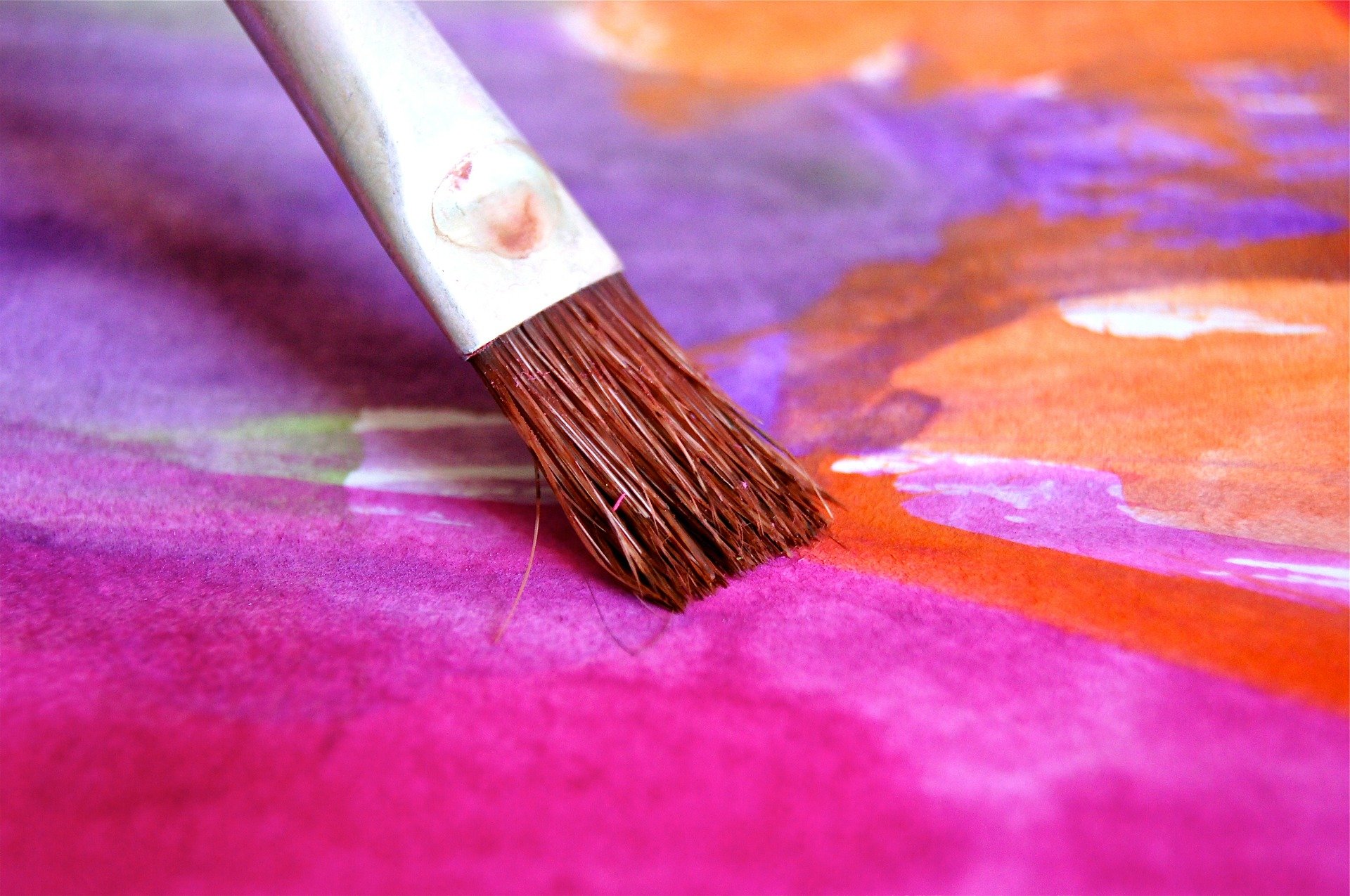a paintbrush on pastel pink, purple and orange watercolour